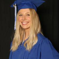 woman wears her cap and gown for a picture at GradFest